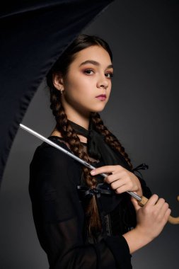 Örgülü bir kız, gotik bir Çarşamba elbisesi içinde, Cadılar Bayramı ruhunu zerafetle somutlaştırıyor..