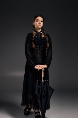 Örgülü bir kız, ürkütücü bir Çarşamba karakterinden esinlenerek gotik bir elbise giyer ve Cadılar Bayramı ruhunu kucaklar..