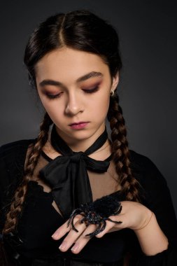 Örgü ören kız gotik bir elbise giyiyor, Çarşamba günü örümcekli ürkütücü bir karakteri somutlaştırıyor.