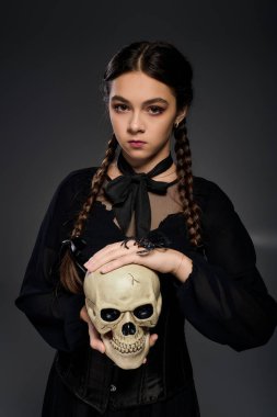 Gotik elbiseli bir kız kafatası tutuyor, cadılar bayramı ve çarşamba ruhunu yakalıyor..