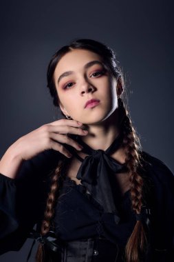 Saçları örgülü bir kız, gotik bir elbise içinde, Cadılar Bayramı ruhunu kucaklıyor ve ürkütücü bir sezon geçiriyor..