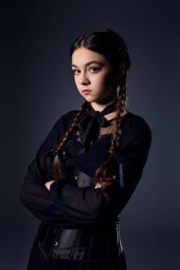 Çarşamba kostümü giymiş genç bir kız cadılar bayramı karakterini örgü örüp tavır takınıyor..