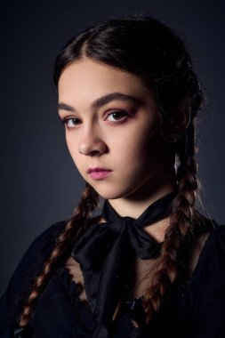 Örgülü bir kız popüler bir Cadılar Bayramı karakterinden esinlenerek gotik bir elbise giyer..