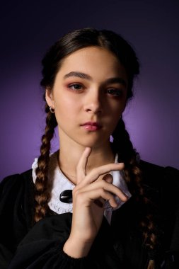 Örgülü bir kız gotik bir elbise giyer, Cadılar Bayramı ve sonbahar eğlencesinin özünü yakalar..