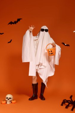 Neşeli bir hayalet gibi giyinmiş bir çocuk, Cadılar Bayramı süslemelerinin arasında eğleniyor..