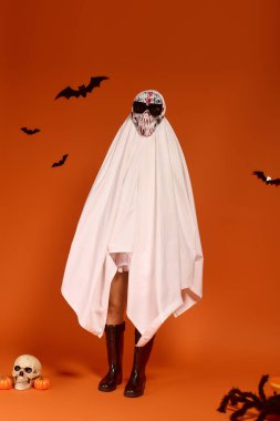 Bir çocuk Cadılar Bayramı 'nı bir hayalet kostümüyle kutluyor. Etrafı şenlikli süslerle çevrili..