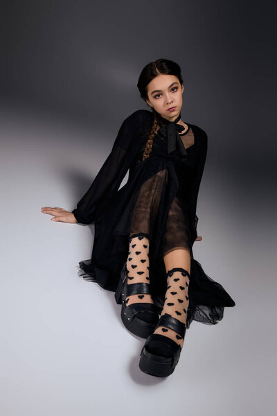 Девушка с косичками носит платье в готическом стиле в среду на Хэллоуин, обнимая жуткий сезон.