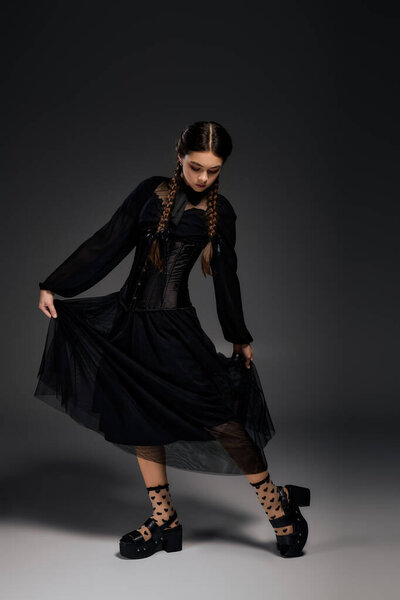 A girl with braids showcases her gothic dress for Halloween, embodying the perfect spooky spirit.