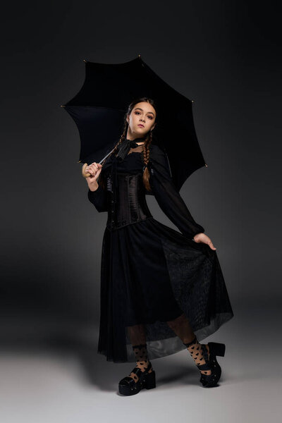 A girl with braids poses elegantly in a gothic dress, capturing the Halloween spirit beautifully.
