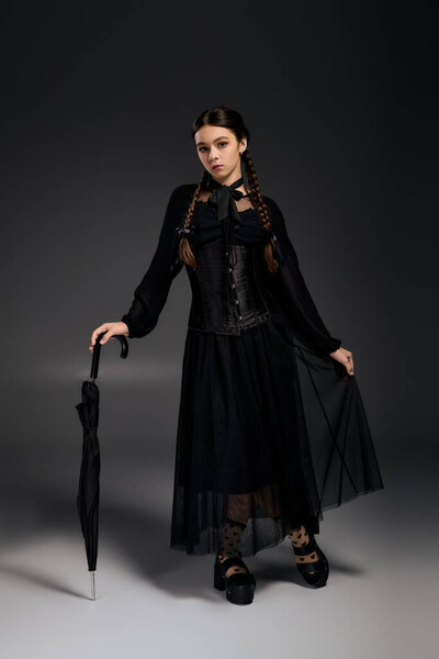 A young girl with braids wears a striking gothic Wednesday dress, perfect for Halloween celebrations.