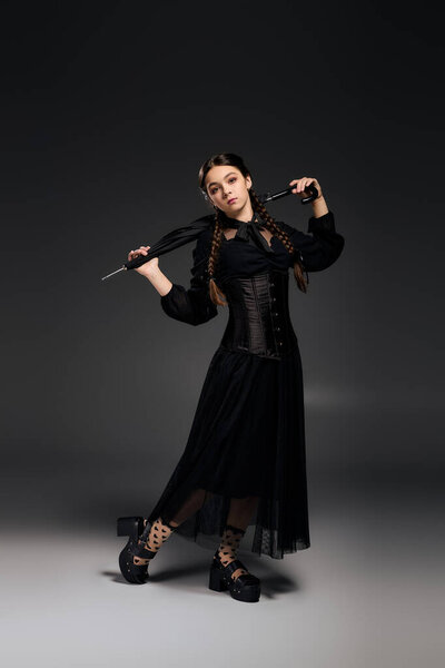 A girl with braids is dressed in a gothic Wednesday costume, channeling a spooky character vibe.