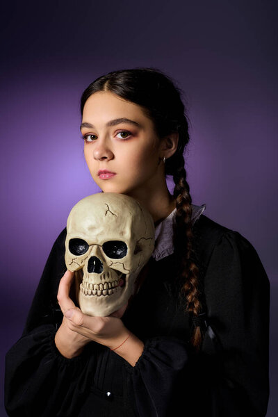 This young girl dressed as a Wednesday character holds a skull, embracing Halloween eerie charm.