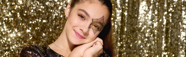 Восхитительная девушка показывает свою звездную краску, окруженная блестящими золотыми блестками на Хэллоуин, баннер
