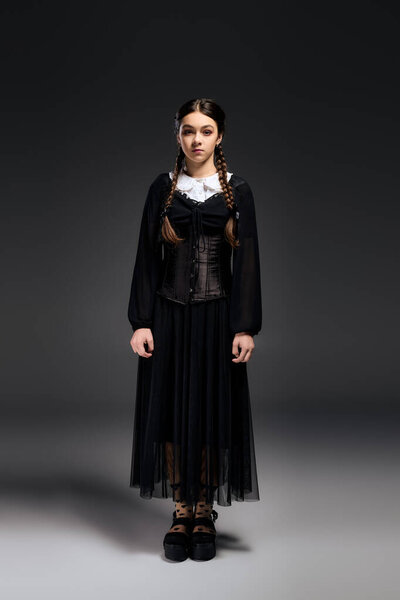 A girl with braids wears a gothic dress inspired by the Wednesday character during Halloween time.