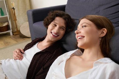A young couple enjoys each others company while relaxing on the floor in their cozy living space.