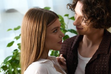 A happy couple enjoys their time together in a stylish and warm apartment filled with plants.