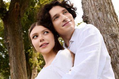 A joyful couple shares a loving moment in nature, embracing under the sun.