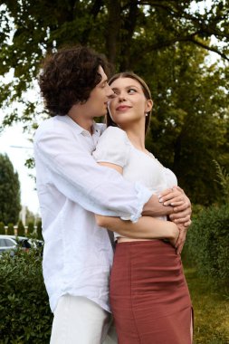 Happy young couple embraces in a beautiful outdoor setting, sharing love and joy.