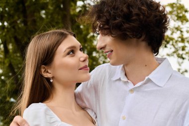 A happy young couple sharing a tender moment under the trees, deeply in love.