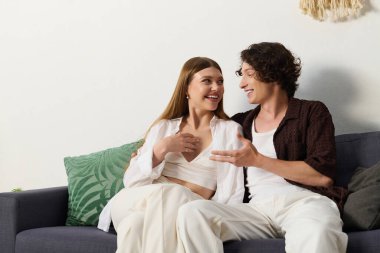 Young couple shares laughter and love while relaxing in their modern living space.