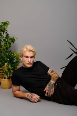 Genç yakışıklı adam yeşilliklerle çevrili yerde rahatlar, kendine güveni ve tarzı yayılır..