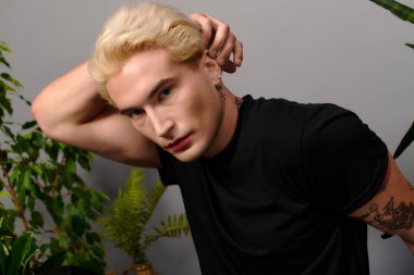 Şık genç, modaya uygun görünümünü ve kendine güvenen duruşunu, canlı bir mekanda sergiliyor.