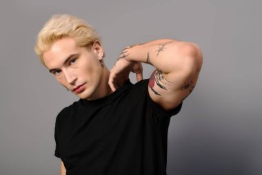 Dövmeleri ve saçı olan şık bir genç. Gençlik kültürünün vücut bulmuş hali..