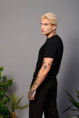 Genç ve yakışıklı bir adam minimalist bir arkaplanda poz veriyor..