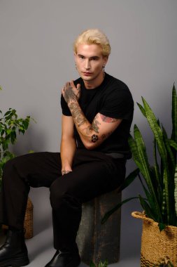 Yakışıklı genç, bitkilerin arasında gençlik tarzını sergiliyor, kendine güven ve cazibe yayıyor.