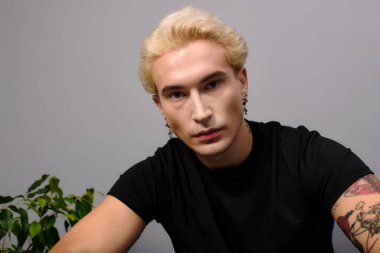 Sarı saçlı genç yakışıklı bir adam modern gençlik kültürünü modaya uygun bir ortamda sergiliyor..