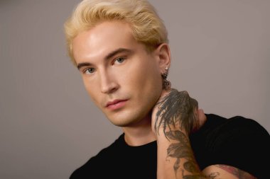 Yakışıklı genç, benzersiz bir stil ve cesur dövmeler sergiliyor. Gençlik cazibesi yayıyor.