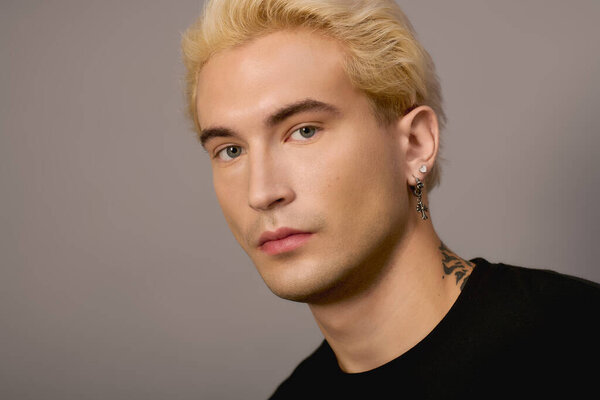 Уверенный подросток демонстрирует свои поразительные черты и модный стиль на простом фоне.