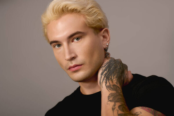 Красивый подросток демонстрирует уникальный стиль и смелые татуировки, источая юное очарование.