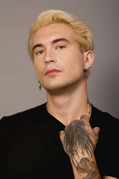 Молодой человек с яркими чертами показывает свой уникальный стиль на простом фоне.