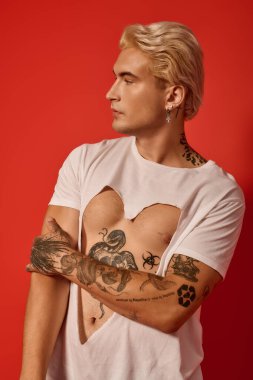 Genç adam stilini ve bireyselliğini çarpıcı bir kırmızı arka plana karşı sergiliyor..