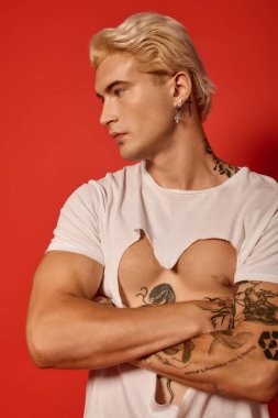 Kendine güvenen, kendine güvenen dövmeleri olan ve eşsiz bir gömlek tasarımı olan genç bir adam..