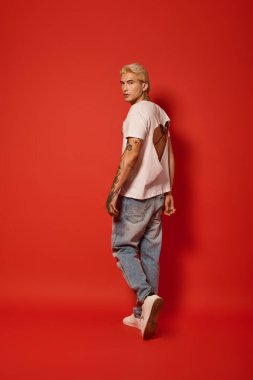 Yakışıklı bir genç, modern gençlik kültürünü özgüvenle ifade eden modaya uygun bir kıyafet sergiliyor..