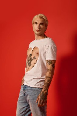 Yakışıklı genç, modaya uygun bir kıyafetle duruyor, gençlik kültürü ve sanatını ön plana çıkarıyor..