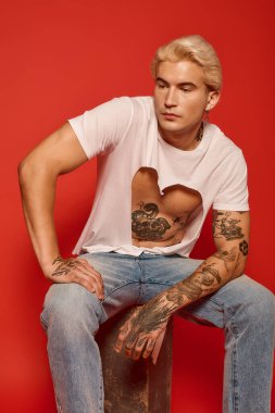 Yakışıklı gençlik kültürü sergiliyor. Stüdyoda şık kıyafetler ve etkileyici dövmeleri var..