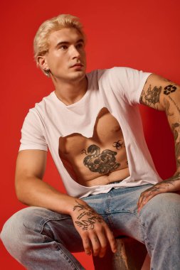 Cesur dövmeleri olan çekici bir genç benzersiz modasını ve gençlik enerjisini sergiliyor..