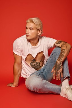 Şık bir genç, modern ve enerjik bir ortamda düşünceli bir şekilde yerde oturuyor..