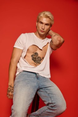 Şık bir genç, parlak kırmızı bir zemin karşısında gençlik kültürünü somutlaştırıyor..