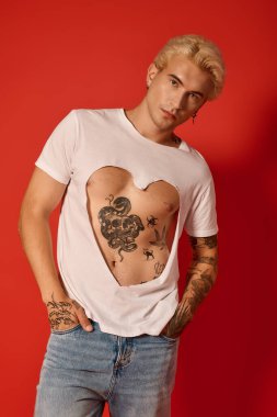 Kendinden emin bir genç gömleğindeki kalp şeklindeki kesiklerle dövmelerini gösteriyor..