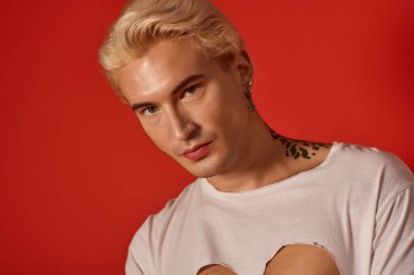 Genç ve yakışıklı bir adam şık kıyafetini ve özgüvenini canlı kırmızı bir fon önünde sergiliyor..