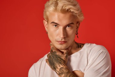 Yakışıklı genç, kendinden emin bir şekilde dövmeleri, karizması ve gençliği ile poz veriyor..