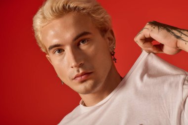 Genç yakışıklı adam gençlik kültürünü ifade ediyor, modaya uygun kıyafetler giyiyor ve kendine güvenini gösteriyor..