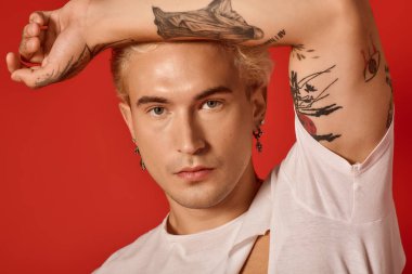Küpeli dövmeli bir genç cesur bir duruş sergiliyor, gençlik kültürü ve tarzını somutlaştırıyor..