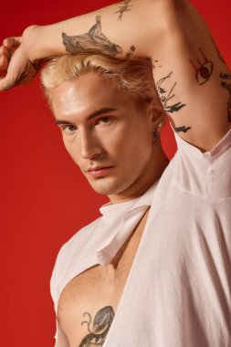 Sarı saçlı ve dövmeli kendinden emin genç adam yaratıcı bir ortamda gençlik kültürü sergiliyor..