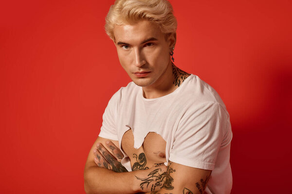 Teenager with tattoos and stylish hair showcases youthful confidence in a bold setting.