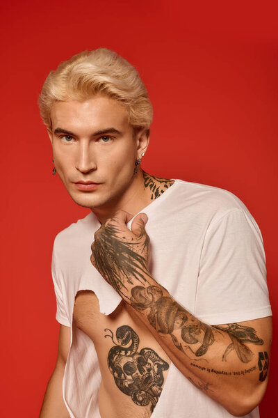 Красивый подросток демонстрирует современную моду с татуировками и уверенным стилем в художественной обстановке.